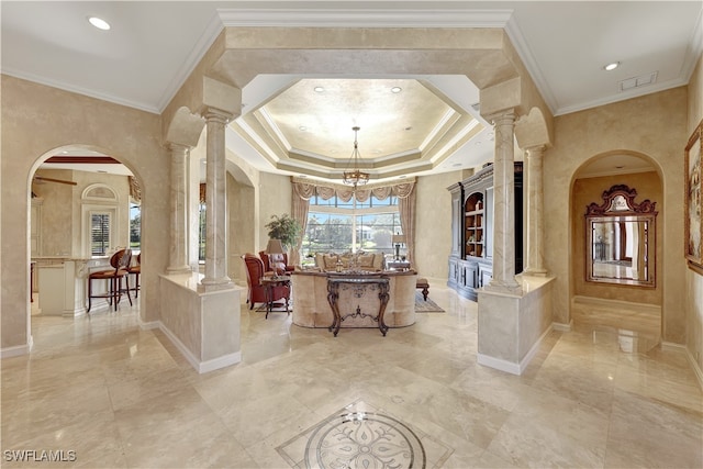 interior space featuring ornate columns, crown molding, a tray ceiling, and an inviting chandelier