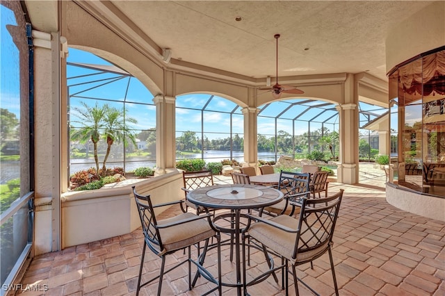 view of patio / terrace with a water view, ceiling fan, and a lanai