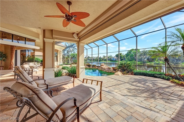 view of patio / terrace with a water view, glass enclosure, and ceiling fan