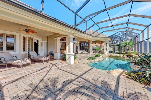 view of swimming pool with glass enclosure, ceiling fan, and a patio