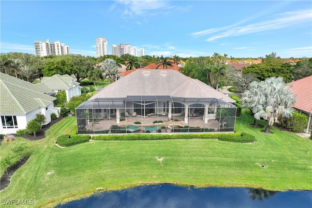 back of property with a lawn, glass enclosure, and a water view