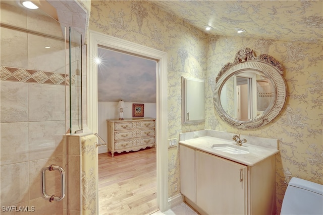 bathroom featuring hardwood / wood-style floors, vanity, lofted ceiling, and toilet