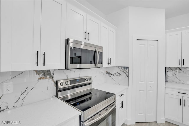 kitchen with white cabinets, backsplash, stainless steel appliances, and light stone countertops