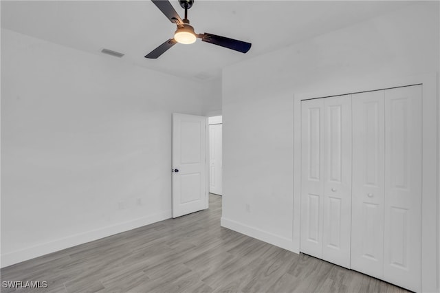 unfurnished bedroom with ceiling fan, a closet, and light wood-type flooring