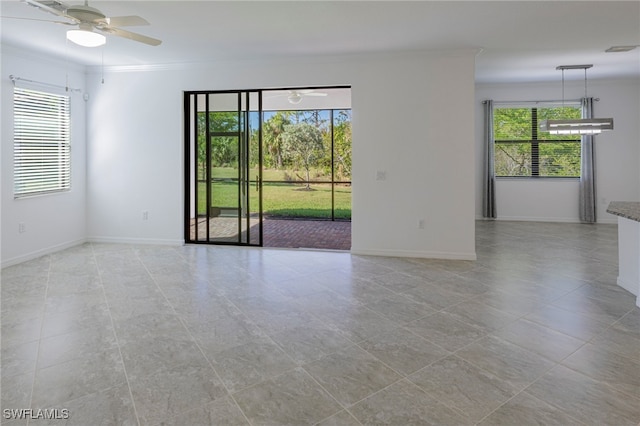 unfurnished room with a wealth of natural light, crown molding, ceiling fan, and light tile patterned floors