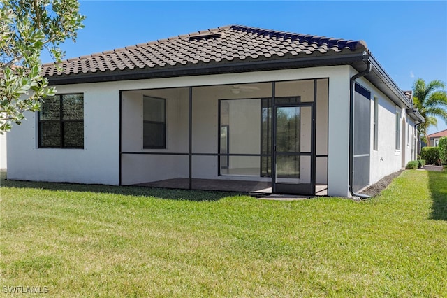 back of property with a lawn and a sunroom