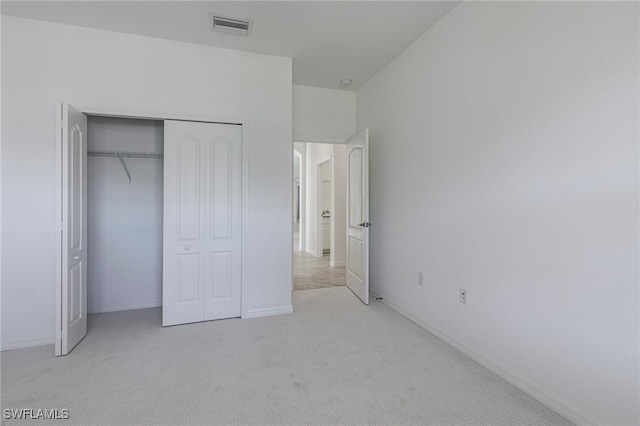 unfurnished bedroom with light carpet and a closet