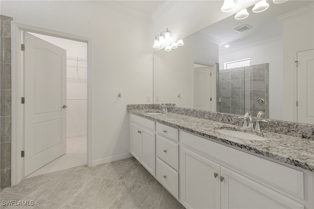 bathroom featuring tile patterned floors, vanity, a tile shower, and crown molding