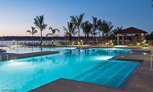 pool at dusk featuring a gazebo and a patio area