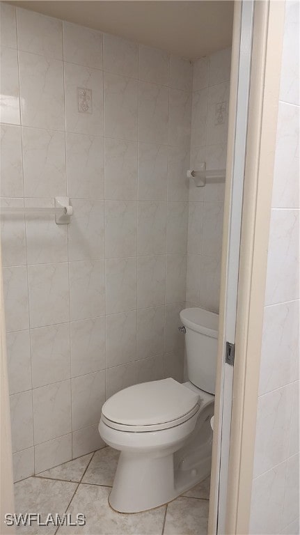 bathroom featuring tile patterned floors, toilet, and tile walls