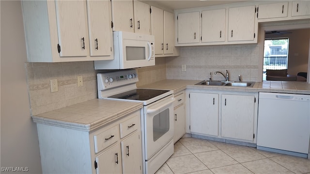 kitchen with light tile patterned flooring, sink, backsplash, tile counters, and white appliances