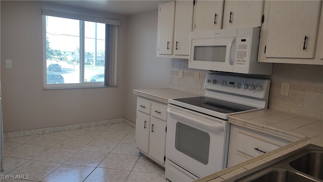 kitchen with tile countertops, white appliances, backsplash, white cabinets, and light tile patterned floors