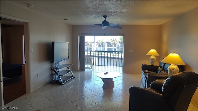 tiled living room with ceiling fan and a textured ceiling