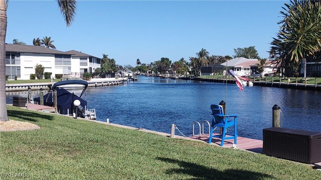 view of dock with a yard and a water view