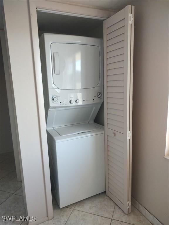 laundry area with stacked washer and dryer and light tile patterned flooring