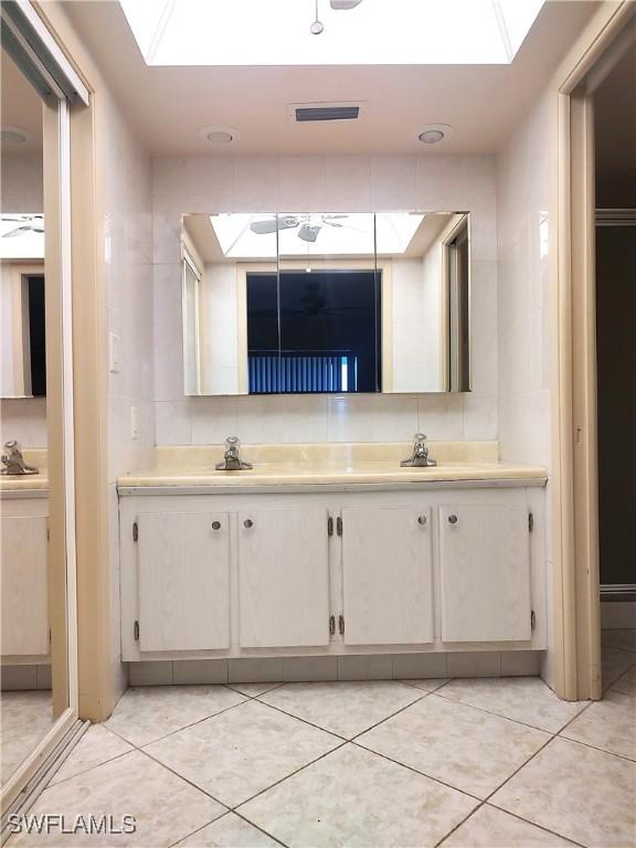 bathroom with tile patterned floors, vanity, and a skylight