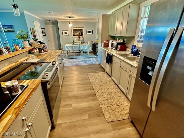 kitchen with crown molding, hanging light fixtures, appliances with stainless steel finishes, and wooden counters