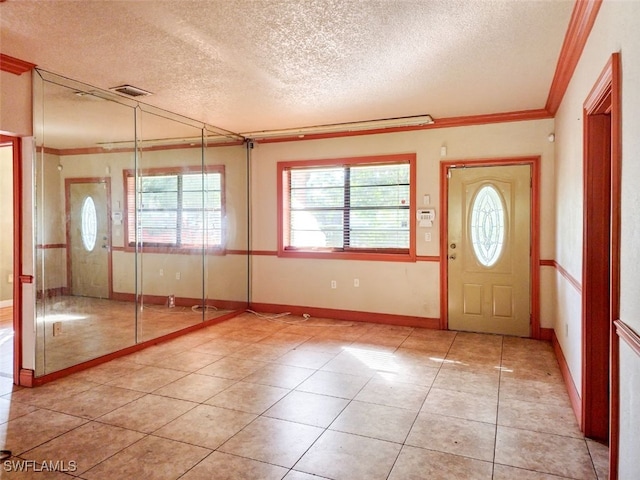 tiled entrance foyer featuring crown molding, a healthy amount of sunlight, and a textured ceiling