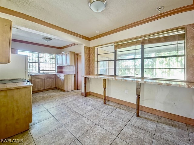 kitchen featuring light tile patterned floors, ornamental molding, a textured ceiling, and white refrigerator