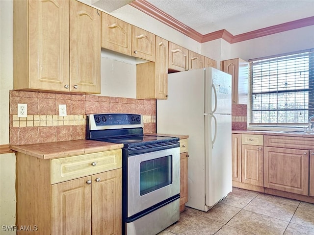 kitchen with a textured ceiling, crown molding, tile countertops, stainless steel electric range, and light tile patterned flooring