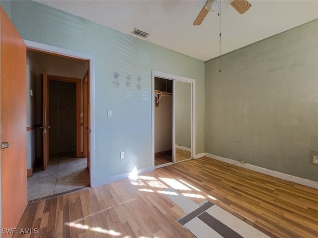 unfurnished bedroom with wood-type flooring, a closet, and ceiling fan