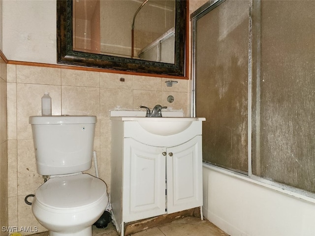 full bathroom featuring vanity, bath / shower combo with glass door, and tile walls