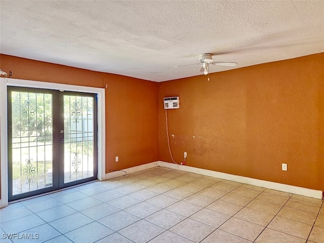 tiled spare room with an AC wall unit, ceiling fan, french doors, and a textured ceiling