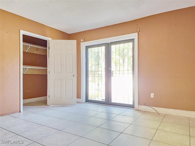 empty room with light tile patterned floors and french doors