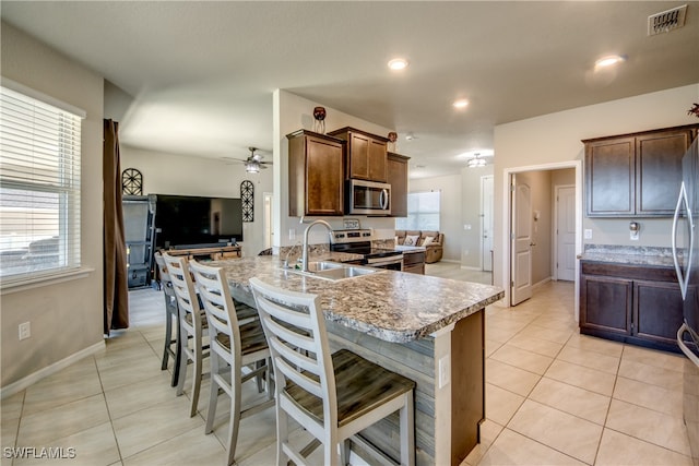 kitchen featuring a breakfast bar, sink, light tile patterned floors, appliances with stainless steel finishes, and kitchen peninsula