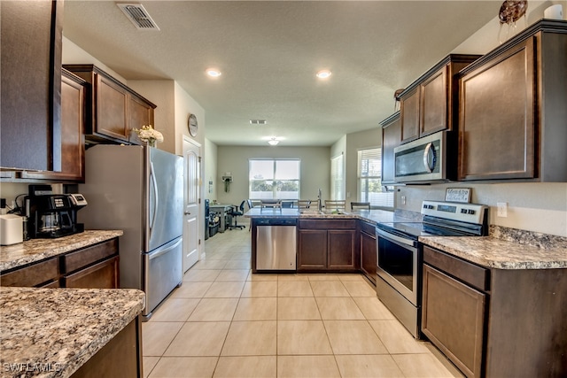 kitchen featuring appliances with stainless steel finishes, light tile patterned floors, dark brown cabinets, and sink