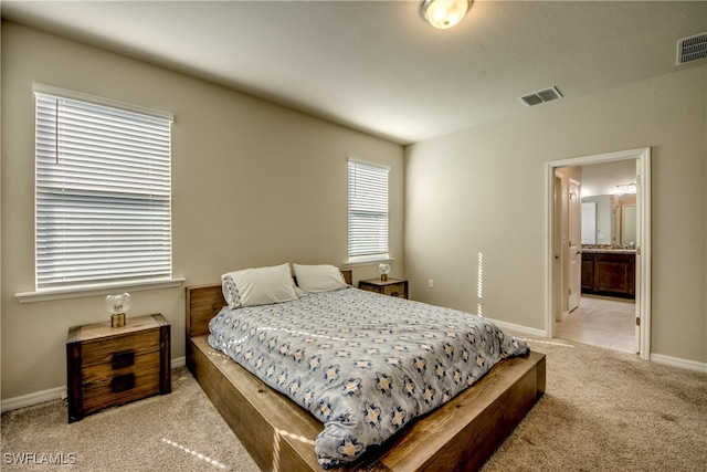 bedroom with light carpet and ensuite bath