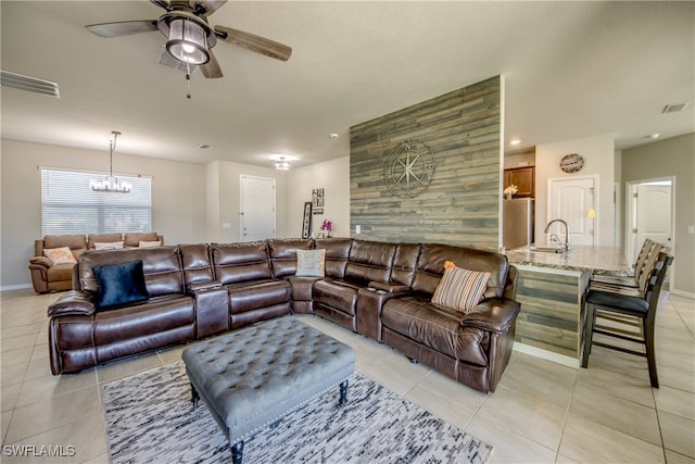 tiled living room featuring ceiling fan with notable chandelier and sink