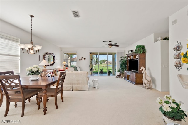 carpeted dining area with ceiling fan with notable chandelier