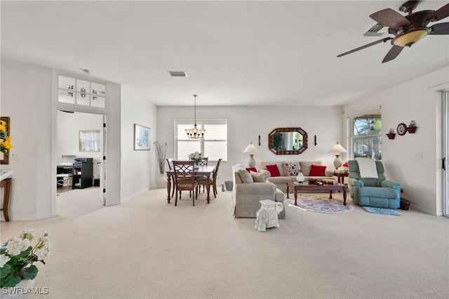 living room with ceiling fan with notable chandelier and light colored carpet