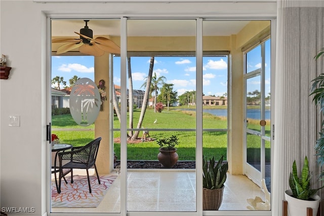 sunroom / solarium featuring ceiling fan and a water view