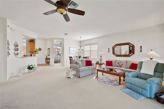 carpeted living room with ceiling fan with notable chandelier