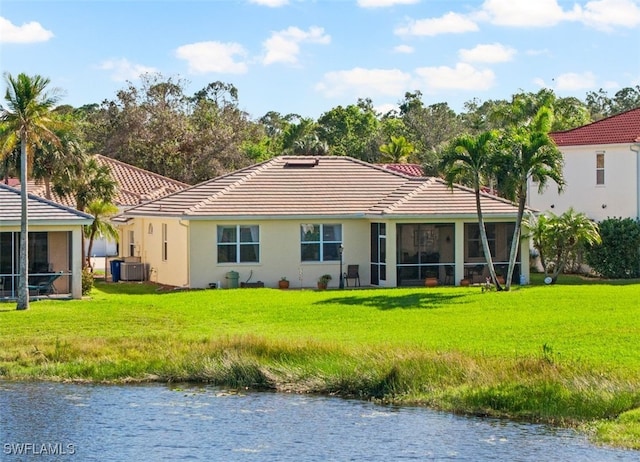 rear view of house with a yard, a water view, central AC, and a sunroom