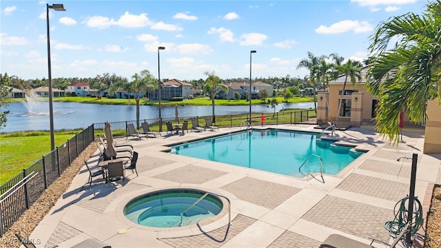 view of pool with an in ground hot tub, a water view, and a patio