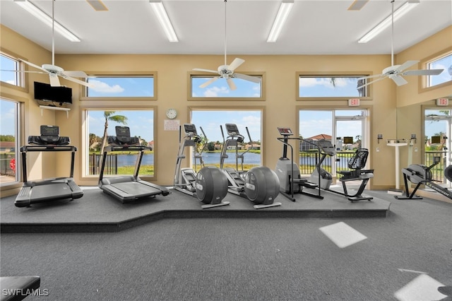 exercise room featuring carpet, ceiling fan, a towering ceiling, and a healthy amount of sunlight