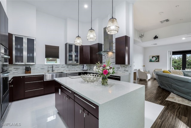 kitchen with decorative backsplash, a kitchen island, a towering ceiling, and sink