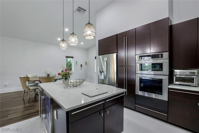 kitchen featuring dark brown cabinetry, hanging light fixtures, stainless steel appliances, light hardwood / wood-style flooring, and a kitchen island