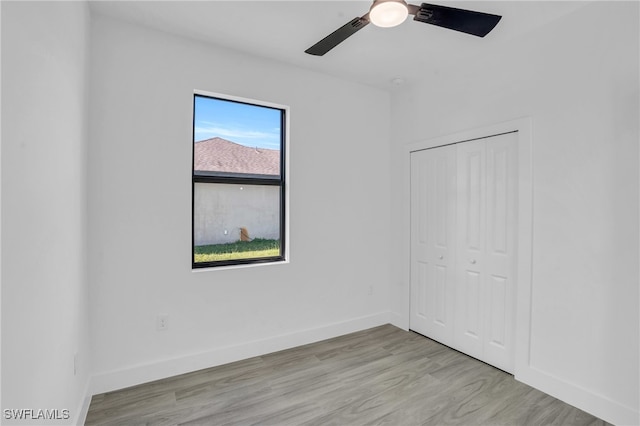 unfurnished bedroom featuring ceiling fan, light hardwood / wood-style floors, and a closet