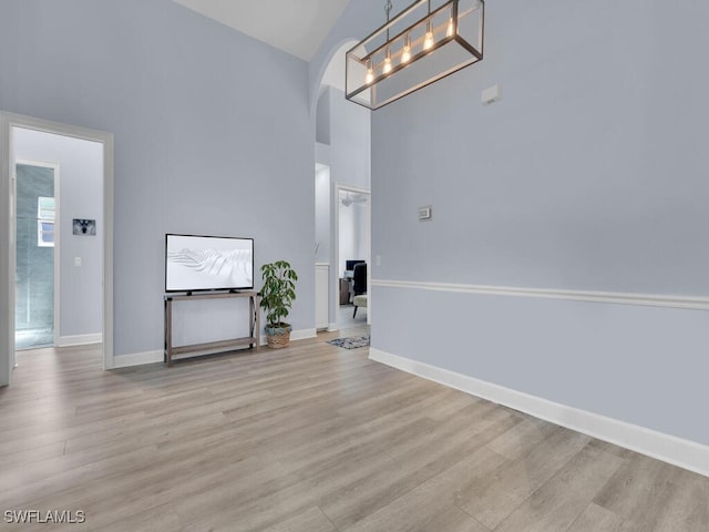 interior space with light hardwood / wood-style flooring, high vaulted ceiling, and an inviting chandelier