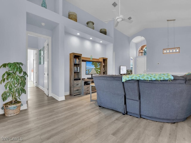 living room featuring ceiling fan, high vaulted ceiling, and wood-type flooring