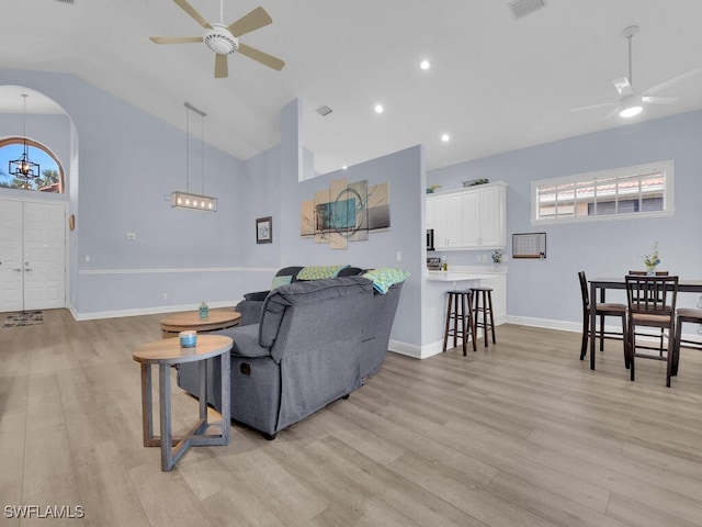 living room featuring ceiling fan with notable chandelier, light hardwood / wood-style flooring, and lofted ceiling