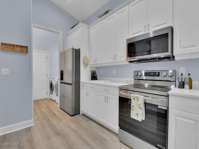 kitchen with washer and dryer, white cabinetry, stainless steel appliances, and light hardwood / wood-style flooring