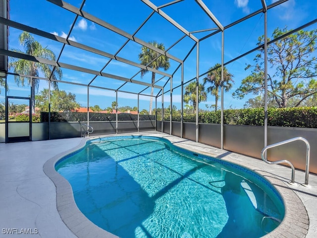 view of swimming pool with glass enclosure and a patio area