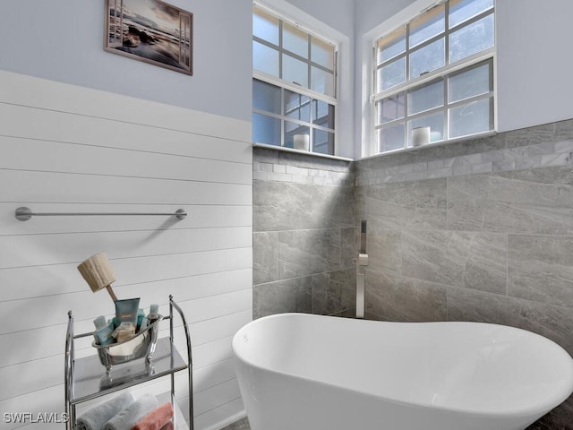 bathroom with a bathtub and tile walls