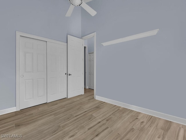 unfurnished bedroom featuring a high ceiling, a closet, light hardwood / wood-style flooring, and ceiling fan