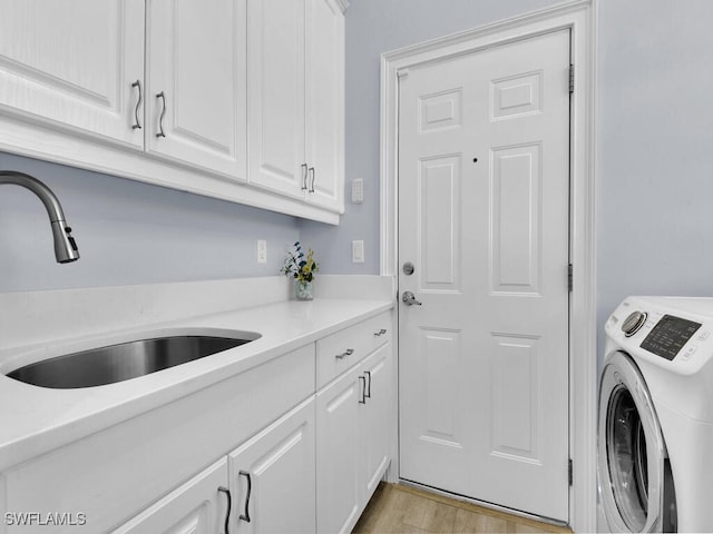 clothes washing area featuring cabinets, washer / clothes dryer, light hardwood / wood-style floors, and sink